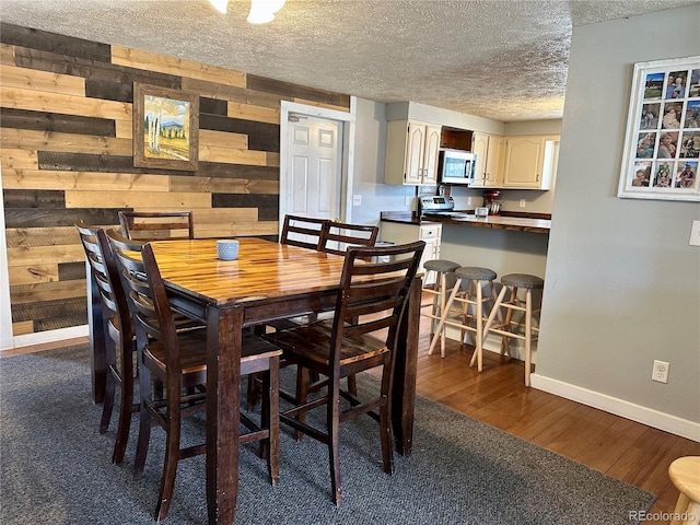 98 Baylor Dr, Buena Vista, CO 81211 - dining area featuring a textured ceiling, wood walls, baseboards, and dark wood-style floors