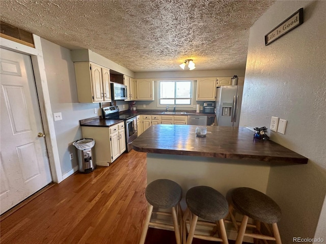 98 Baylor Dr, Buena Vista, CO 81211 - kitchen featuring appliances with stainless steel finishes, a textured ceiling, a peninsula, a breakfast bar, and wood finished floors