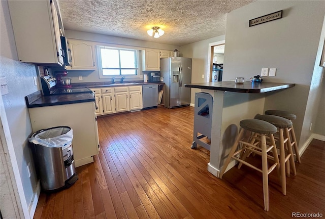 98 Baylor Dr, Buena Vista, CO 81211 - kitchen featuring stainless steel appliances, dark countertops, a kitchen bar, a sink, and hardwood / wood-style floors