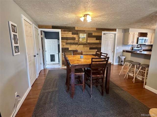 98 Baylor Dr, Buena Vista, CO 81211 - dining room featuring a textured ceiling, dark wood-style flooring, baseboards, and wood walls