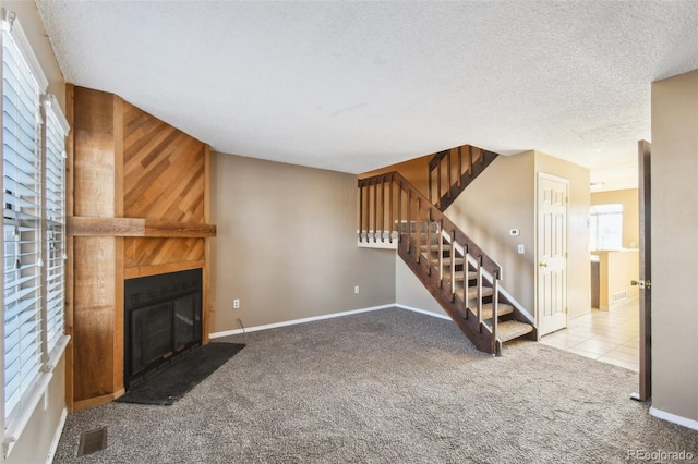 unfurnished living room with a large fireplace, carpet floors, and a textured ceiling