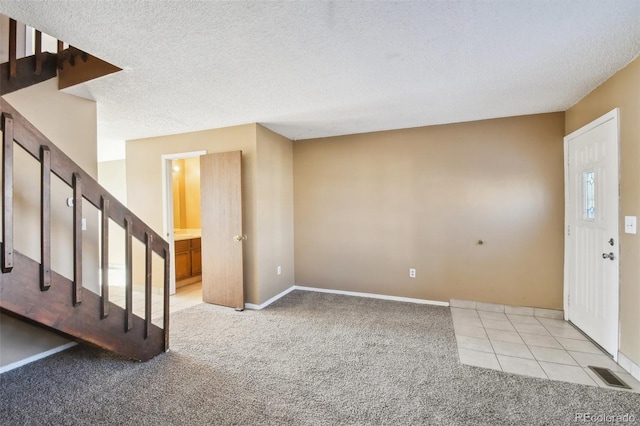 carpeted foyer featuring a textured ceiling