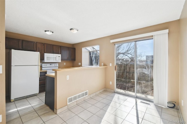 kitchen featuring kitchen peninsula, light tile patterned floors, white appliances, and dark brown cabinetry