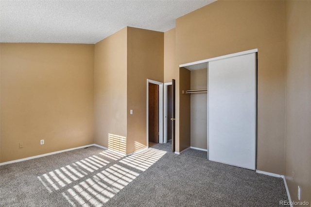 unfurnished bedroom with a textured ceiling, carpet floors, a closet, and lofted ceiling