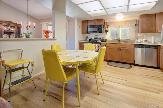 dining room with vaulted ceiling, a chandelier, sink, and light hardwood / wood-style flooring