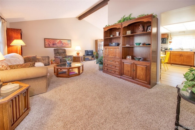 living room with sink, lofted ceiling with beams, and light colored carpet