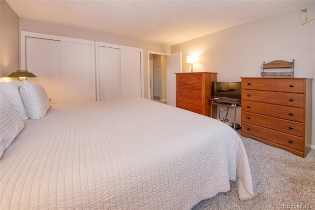 bedroom featuring a textured ceiling, multiple closets, and carpet