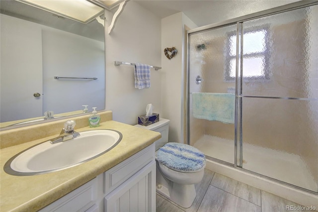 bathroom featuring vanity, a shower with shower door, and toilet