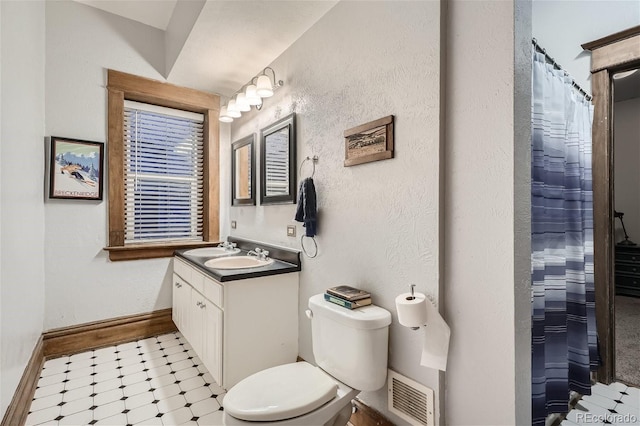 bathroom featuring a textured wall, toilet, vanity, visible vents, and baseboards