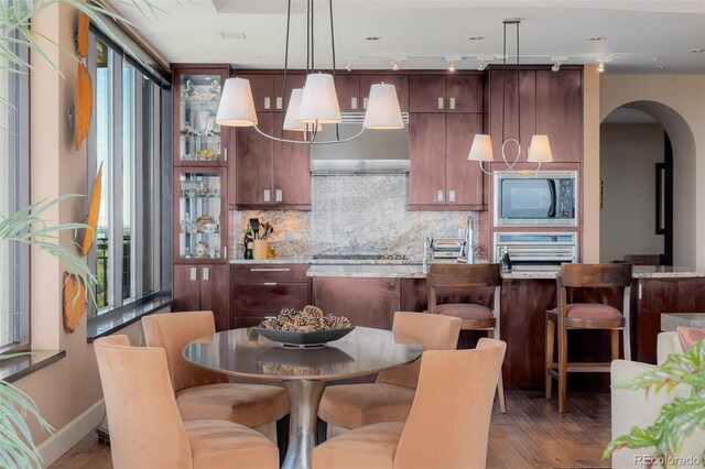 kitchen with cooktop, oven, light stone countertops, dark hardwood / wood-style flooring, and black microwave