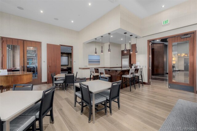 dining room featuring light wood-type flooring and a high ceiling