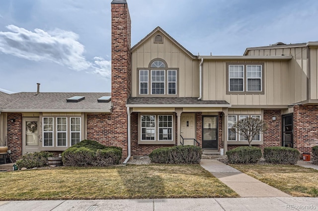 townhome / multi-family property with board and batten siding, a front lawn, and brick siding