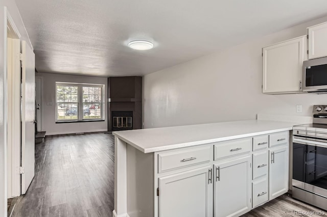 kitchen featuring appliances with stainless steel finishes, a peninsula, light countertops, open floor plan, and a textured ceiling