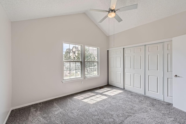 unfurnished bedroom with carpet flooring, vaulted ceiling, a textured ceiling, a closet, and baseboards
