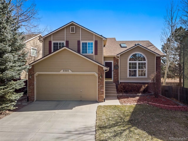 tri-level home with a garage, brick siding, concrete driveway, and fence