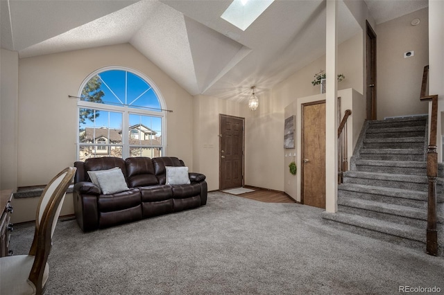 carpeted living room with stairway, a textured ceiling, a skylight, and high vaulted ceiling