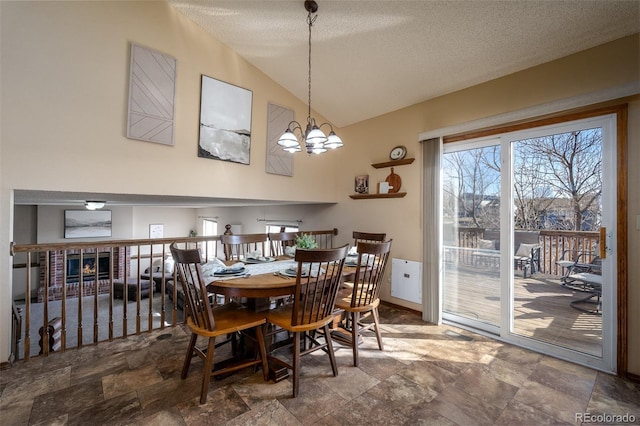 dining area featuring stone finish flooring, lofted ceiling, a textured ceiling, and an inviting chandelier