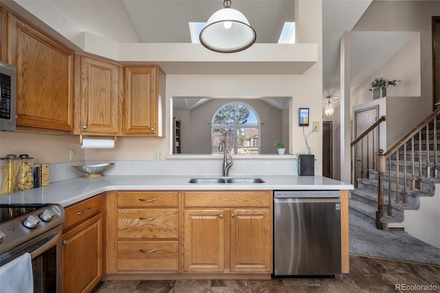 kitchen featuring vaulted ceiling, appliances with stainless steel finishes, light countertops, and a sink