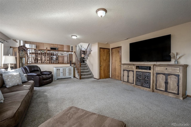 living area with stairs, carpet flooring, and a textured ceiling