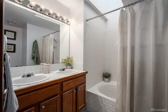 full bathroom with double vanity, visible vents, tiled shower / bath, and a sink