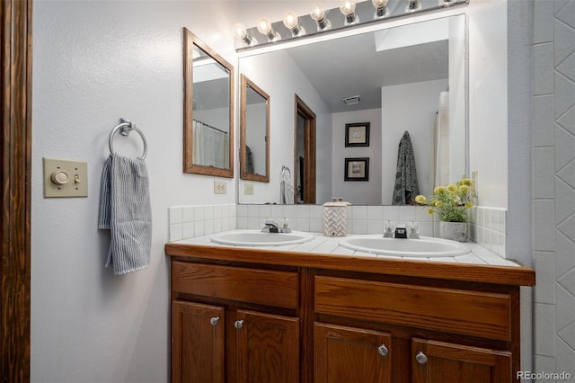 full bathroom with a sink, visible vents, tasteful backsplash, and double vanity