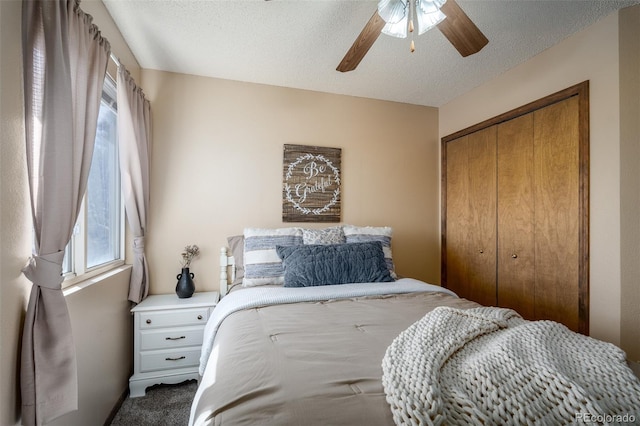 bedroom featuring a ceiling fan, carpet, a closet, and a textured ceiling