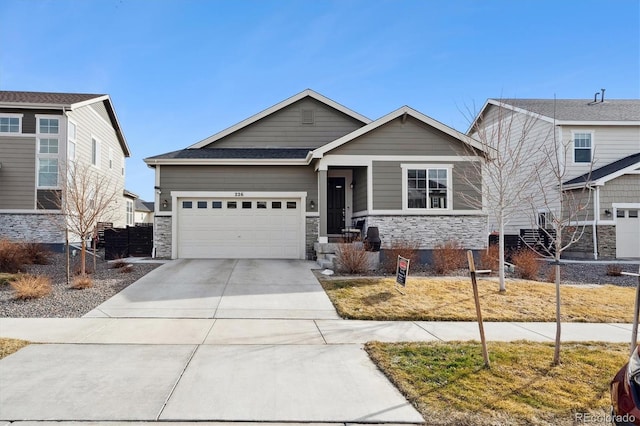 craftsman house featuring a garage, stone siding, concrete driveway, and fence