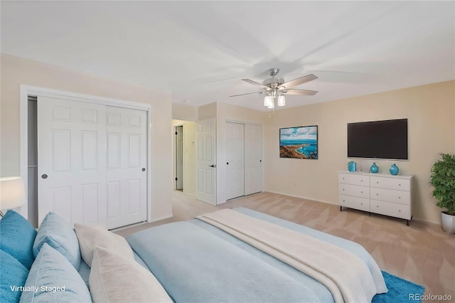 bedroom with two closets, light colored carpet, and ceiling fan