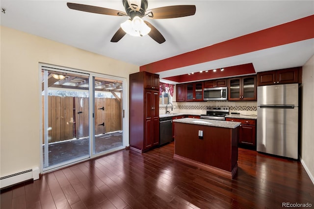 kitchen with sink, a center island, baseboard heating, appliances with stainless steel finishes, and decorative backsplash