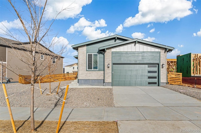 view of front of home featuring driveway, a garage, fence, board and batten siding, and brick siding