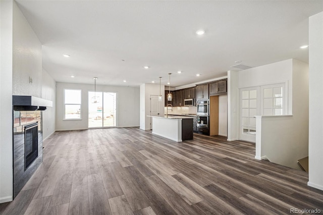 unfurnished living room with dark wood-style floors, recessed lighting, a sink, and a multi sided fireplace