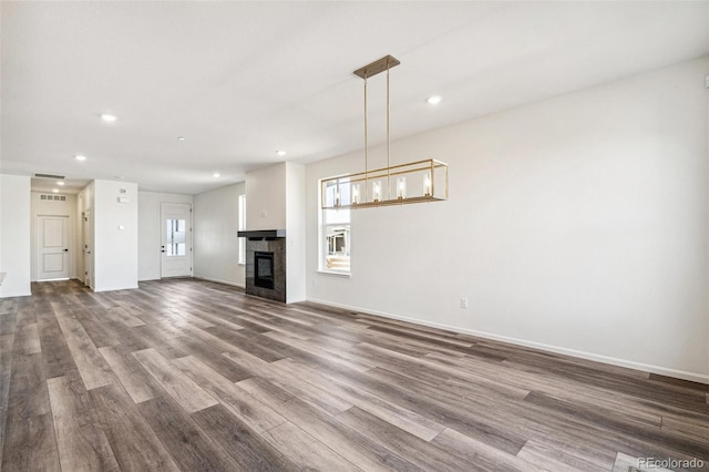 unfurnished living room with a tile fireplace, baseboards, recessed lighting, and wood finished floors