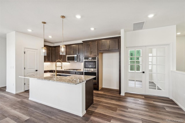 kitchen featuring dark wood finished floors, an island with sink, stainless steel appliances, dark brown cabinets, and a sink