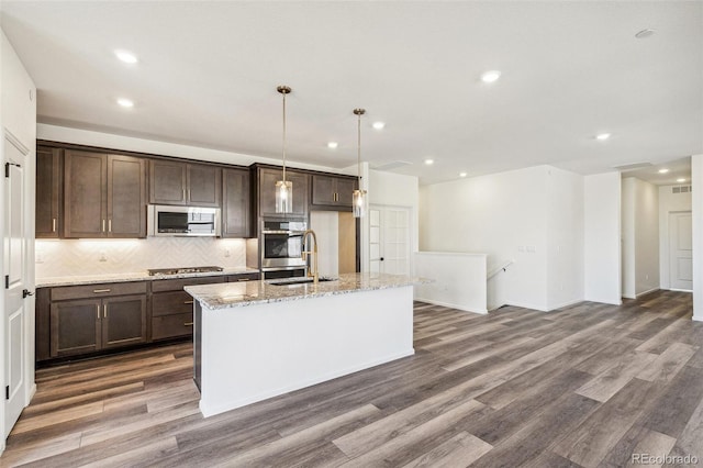 kitchen featuring dark brown cabinetry, decorative backsplash, dark wood-style floors, appliances with stainless steel finishes, and a sink