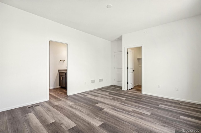 unfurnished bedroom featuring lofted ceiling, baseboards, visible vents, and wood finished floors