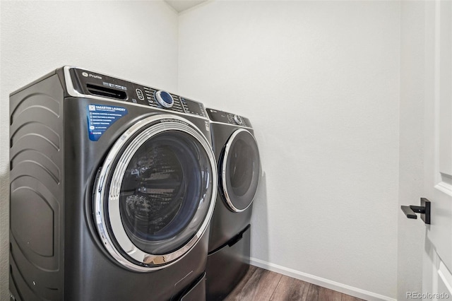 laundry area with laundry area, dark wood-type flooring, washing machine and dryer, and baseboards