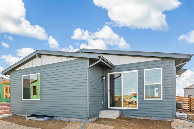 exterior space with central AC unit, board and batten siding, and fence