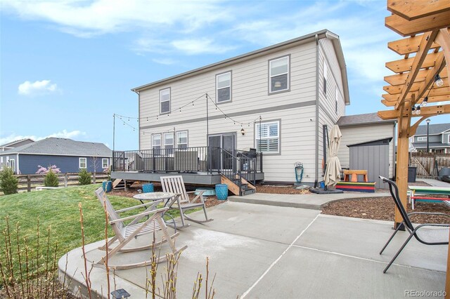 back of house featuring an outdoor structure, a deck, a patio area, a storage shed, and a yard