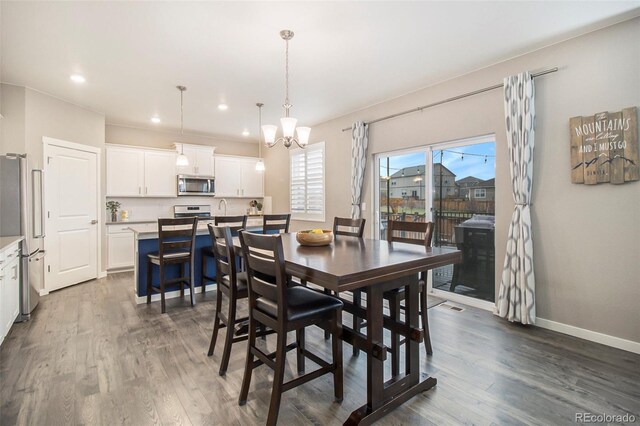 dining room featuring recessed lighting, baseboards, a notable chandelier, and dark wood finished floors
