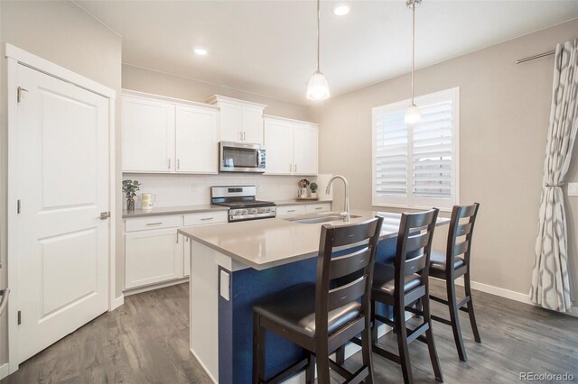 kitchen with decorative backsplash, a breakfast bar area, dark wood-style floors, a sink, and appliances with stainless steel finishes