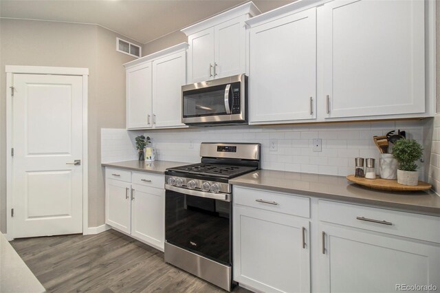 kitchen featuring appliances with stainless steel finishes, white cabinets, tasteful backsplash, and dark wood-type flooring