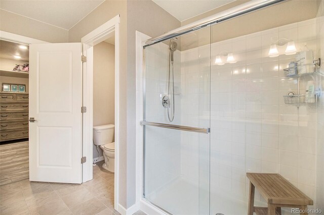 full bath with baseboards, tile patterned flooring, a stall shower, and toilet