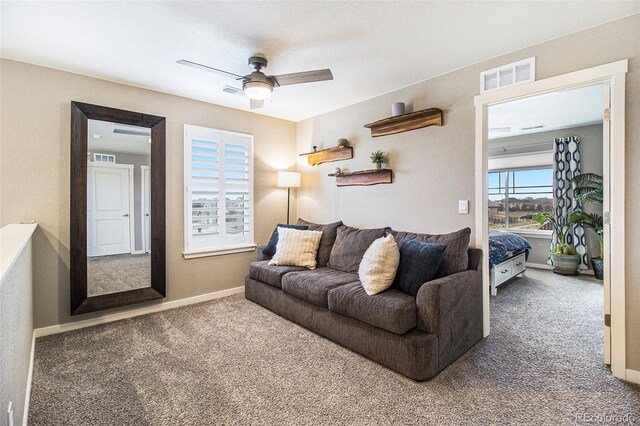 carpeted living area with visible vents, baseboards, and ceiling fan