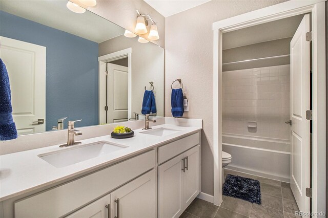 full bathroom with a sink, tile patterned flooring, toilet, and double vanity
