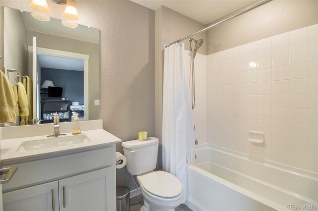 bathroom with toilet, a textured wall, shower / bath combo with shower curtain, and vanity