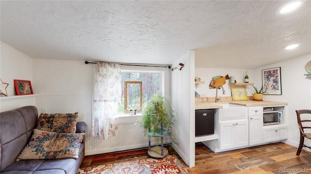 10990 Oehlman Ave, Conifer, CO 80433 - kitchen with stainless steel microwave, light wood-style flooring, white cabinetry, a textured ceiling, and a wainscoted wall