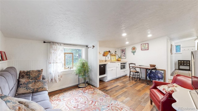 10990 Oehlman Ave, Conifer, CO 80433 - living room with light wood-style flooring, a textured ceiling, a wainscoted wall, and recessed lighting