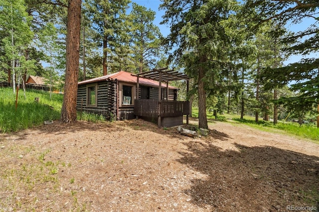 10990 Oehlman Ave, Conifer, CO 80433 - view of front facade with log exterior, dirt driveway, and a wooden deck