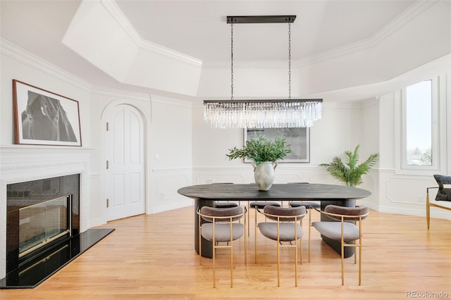 dining space featuring hardwood / wood-style floors, ornamental molding, and a raised ceiling