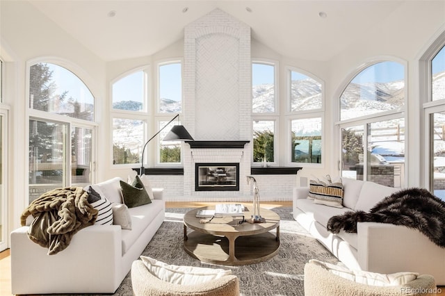 sunroom / solarium featuring vaulted ceiling, a brick fireplace, and a mountain view